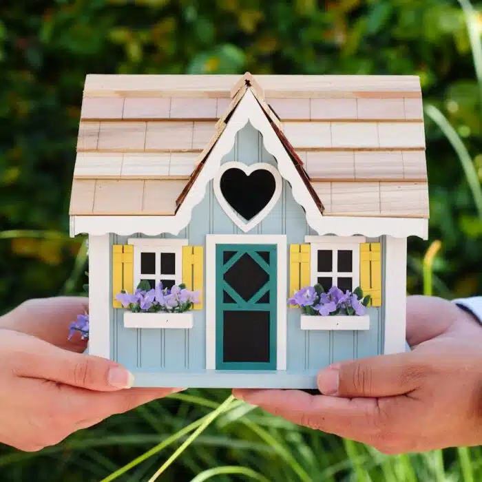 Photo by Kindel Media Close-up of hands holding a detailed miniature house model, symbolizing goals of homeownership and noise surveys for small developments.