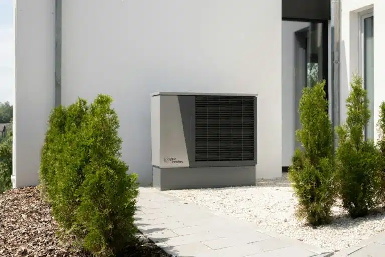 a air conditioner sitting and mounted on the side of a building generating noise. Noise Assessment for Heat Pump Installation with BS 4142 requiring a noise impact assessment for planning and to discharge a planning condition.