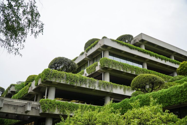 a building with a lot of plants growing on it Cross-laminated timber structure being tested for sound insulation Recycled acoustic panels installed in sustainable building interior Diagram comparing embodied carbon of acoustic partition materials Acoustic consultant conducting field sound test beside eco-building