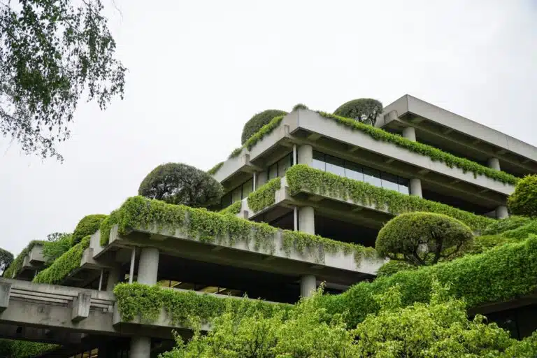 a building with a lot of plants growing on it Cross-laminated timber structure being tested for sound insulation Recycled acoustic panels installed in sustainable building interior Diagram comparing embodied carbon of acoustic partition materials Acoustic consultant conducting field sound test beside eco-building