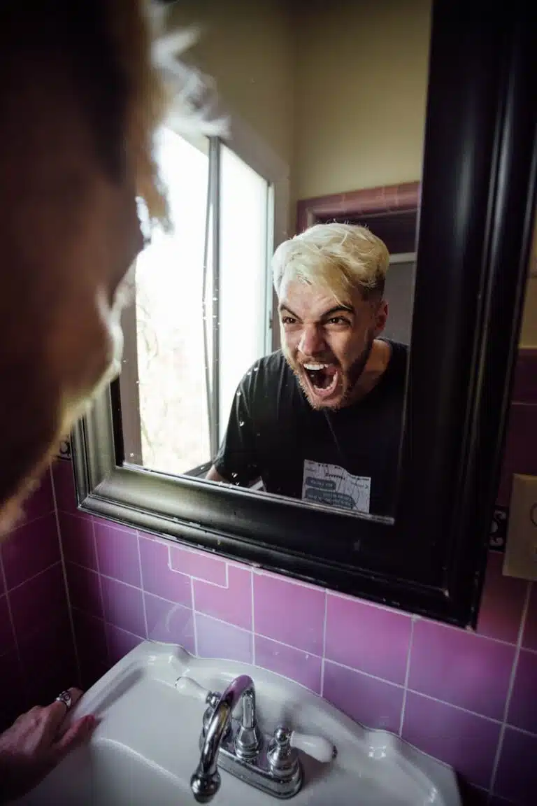 man in black crew neck shirt, screaming at the mirror because he needs to submit a noise complaint and deal with noise nuisance.