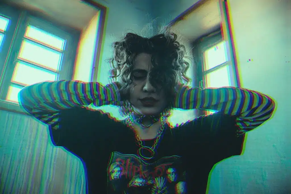 woman in blue and black striped long sleeve shirt covering her ears due to excessive noise. She needs to complain but is too afraid to.