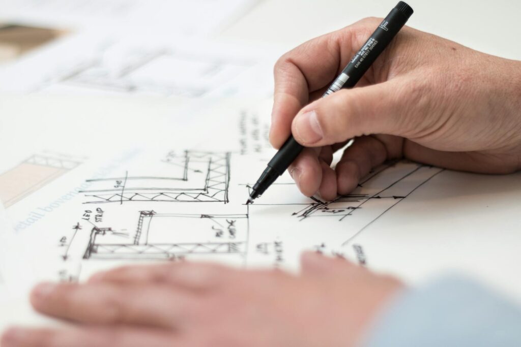 Close-up of hand drawing intricate technical designs on blueprint with pen, ideal for engineering or architecture themes. environmental noise solutions for planning consent.