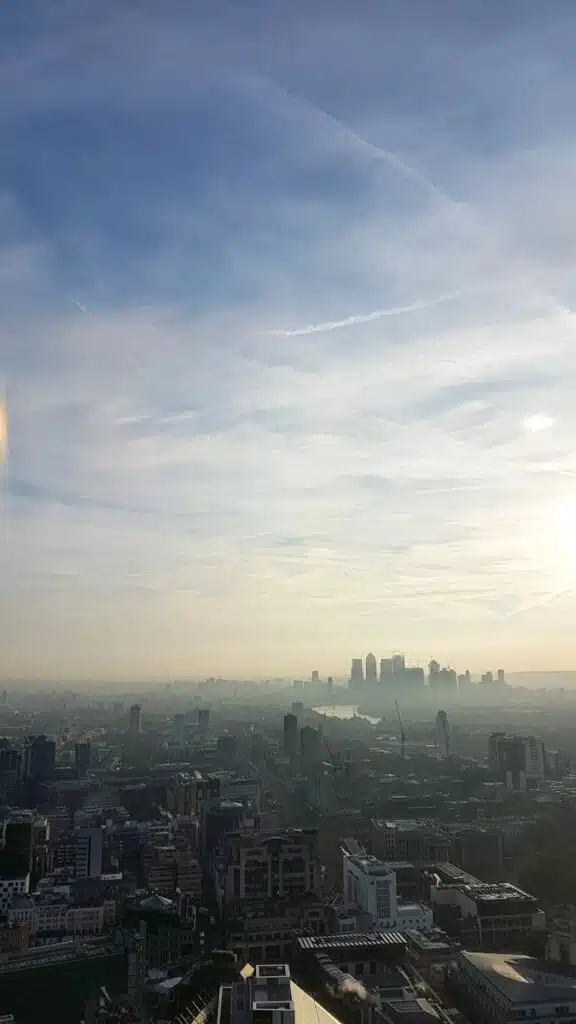 Panoramic view of London's skyline enveloped in fog with iconic skyscrapers and daylight breaking through. noise survey in Greater London.