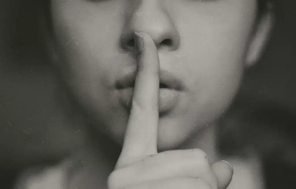 grayscale photo of woman doing silent hand sign. Are air source heat pumps noisy? How to reduce heat pump noise?