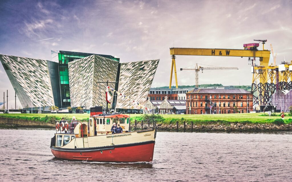 red and white boat on water near green and white building during daytime acoustic consultants in northern ireland