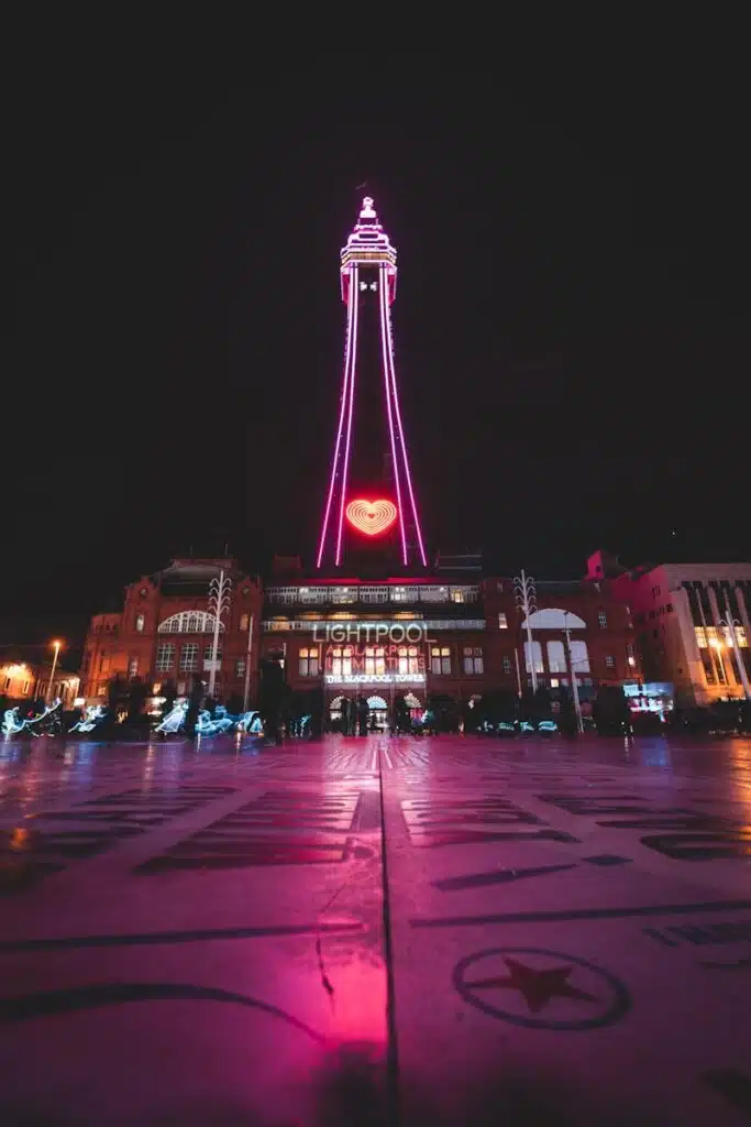 a tall tower lit up at night, the Blackpool Tower. Your #1 North West Acoustic Consultants.