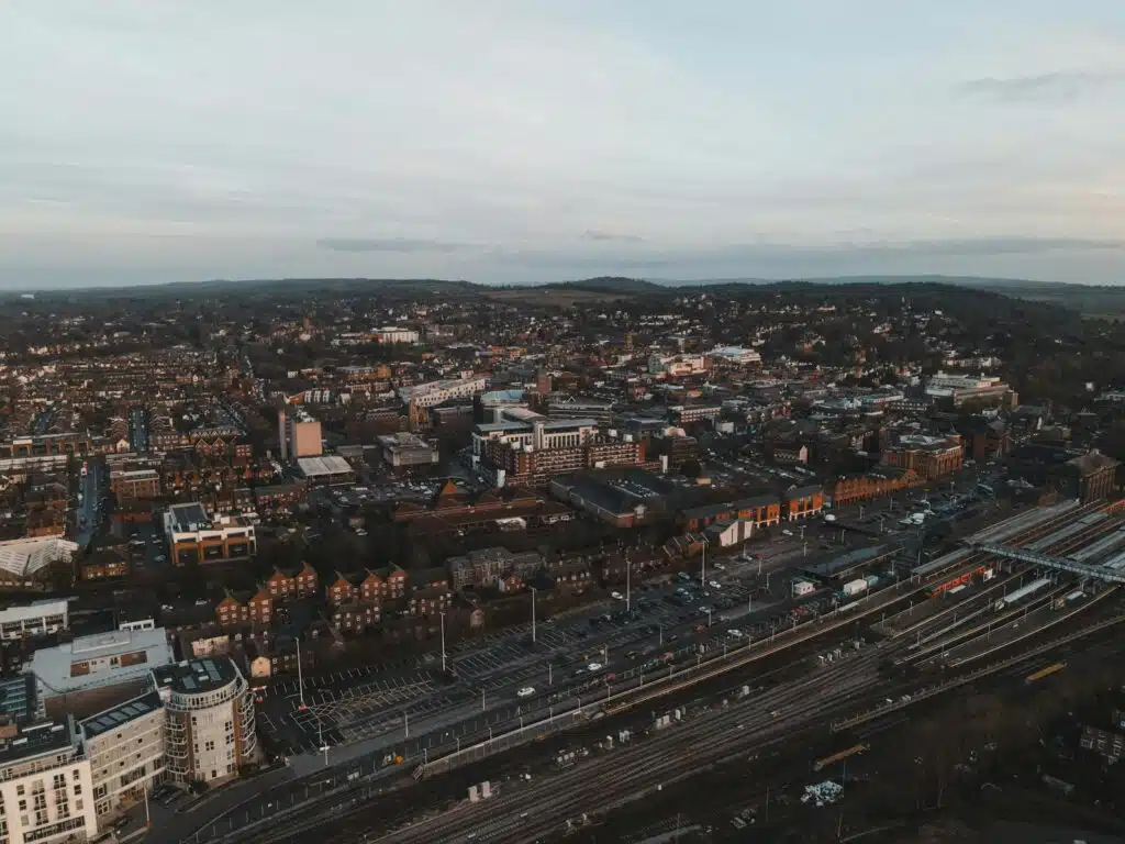Aerial shot of Guildford, UK, showcasing urban cityscape and train tracks at dusk after noise assessment survey.