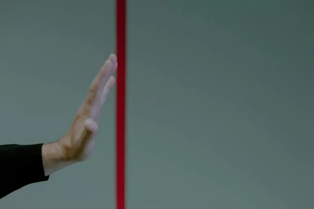 Close-up of a man's hand gesturing stop in front of a vertical red line, concept of boundary and limit, noise level limit. noise limit.