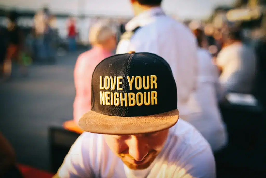 man wearing black cap with love your neighbour print during daytime, noisy neighbour