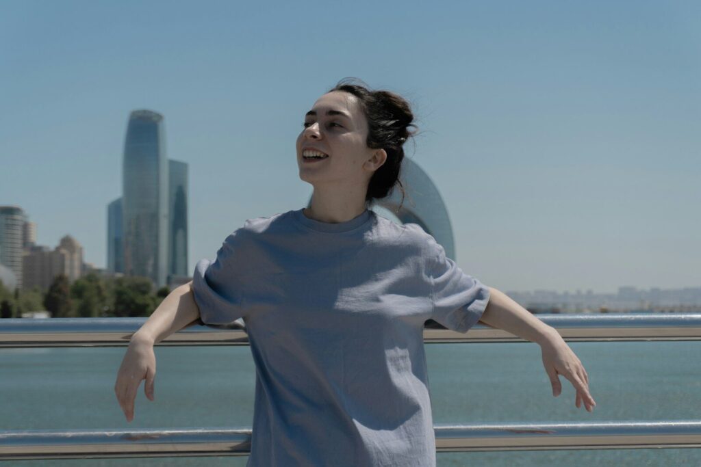 Woman smiles, arms out, overlooking a cityscape. Happy that her acoustic report got her planning permission from Polaris Acoustics.
